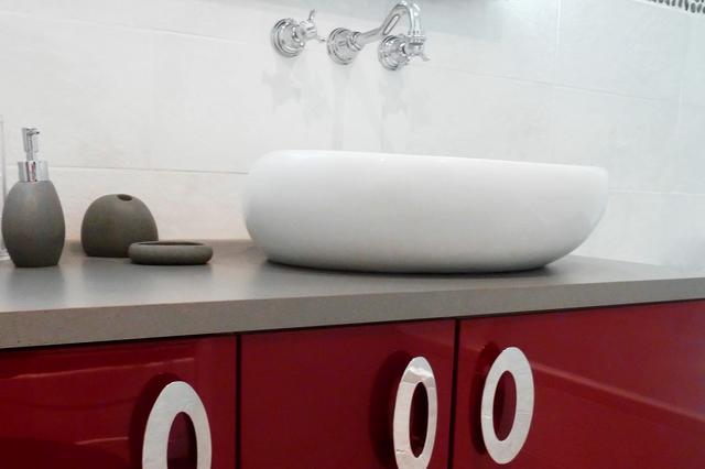 Meuble de salle de bain rouge avec lavabo galet et robinetterie encastrée.