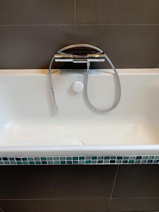 La baignoire avec robinetterie encastrée est mise en valeur par le carrelage gris