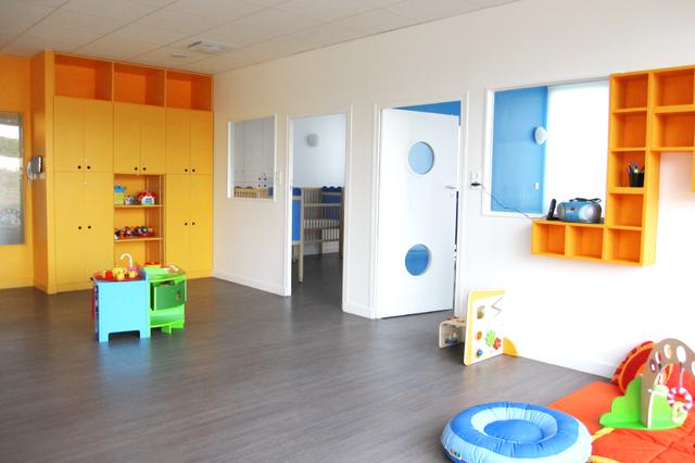 Salle de jeu des tout-petits, les rangements jaunes permettent aux enfants de ranger leur jeu en toute autonomie