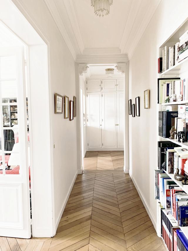 Couloir menant aux chambres rythmé par des étagères et des tableaux
