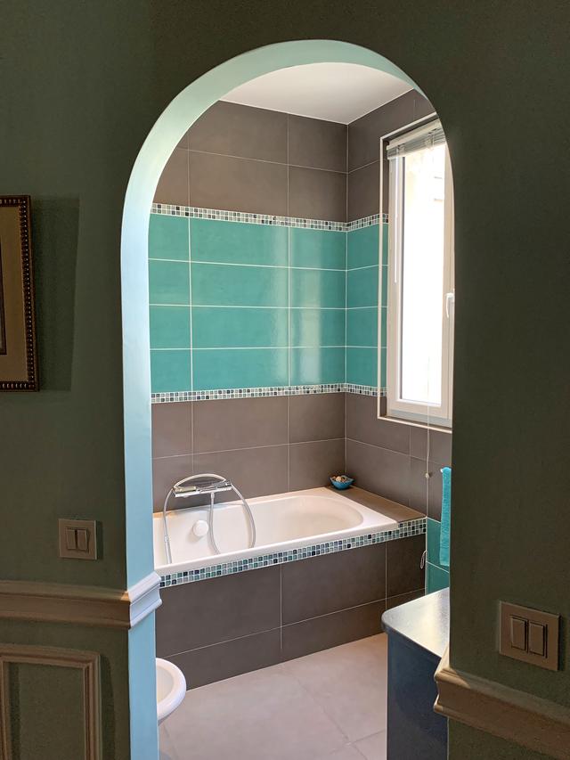 Le carrelage gris anthracite et turquoise est réhaussé d’un liseret en mosaïque