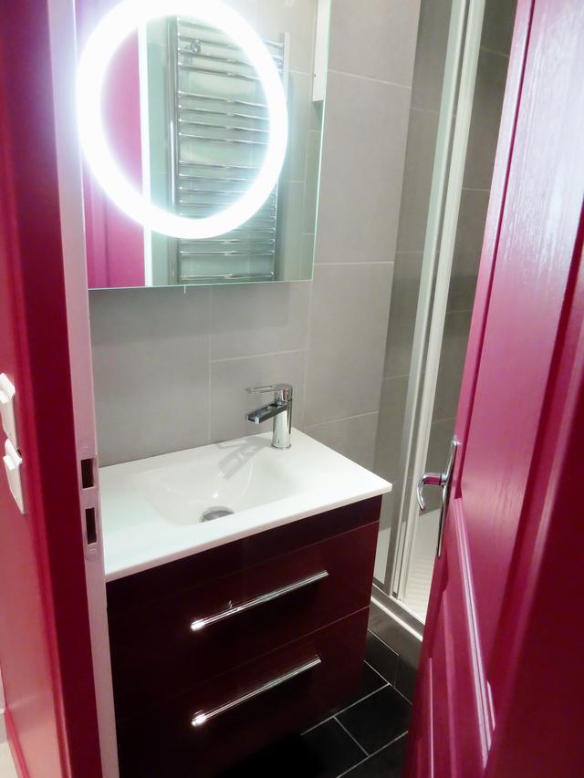 Le meuble vasque framboise et le miroir s’harmonisent avec l’ensemble du studio