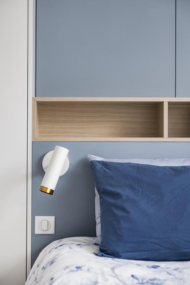 Appliques blanches et laiton en tête de lit.