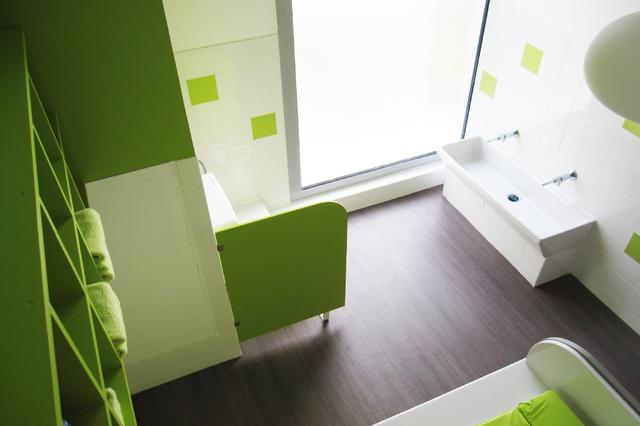 Salle de change à dominante verte avec rangements en hauteur pour la sécurité des petits Salle de change à dominante verte avec rangements en hauteur pour la sécurité des petits